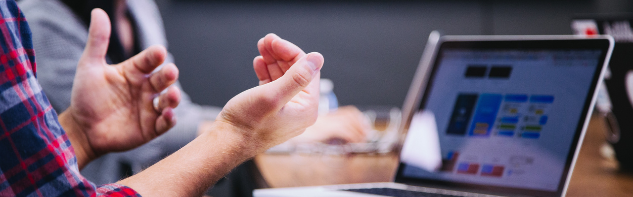 Ein Mann gestikuliert mit seinen Händen bei einem Meeting. 